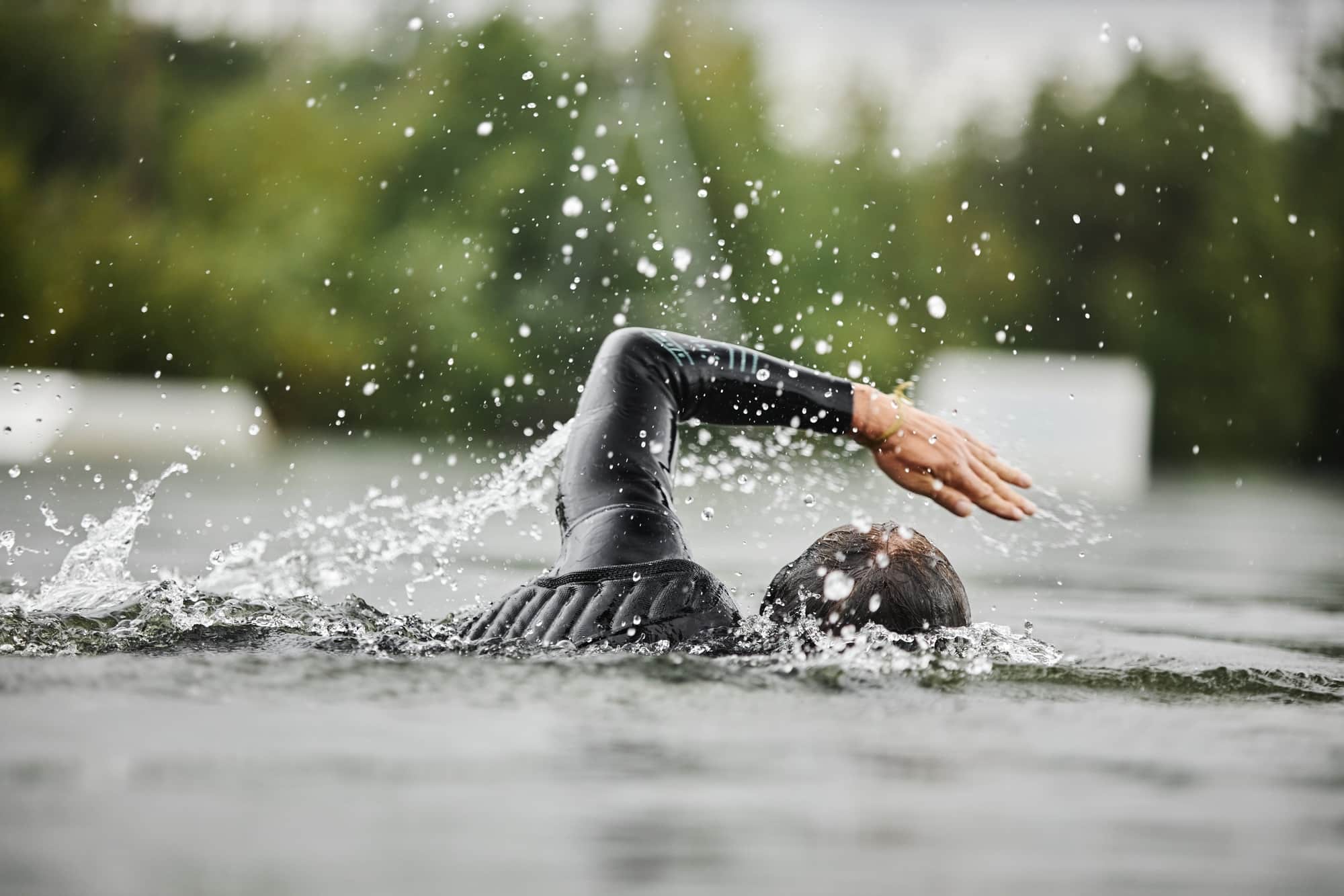 Freiwasserschwimmer im Neoprenanzug mit Wasserspritzern